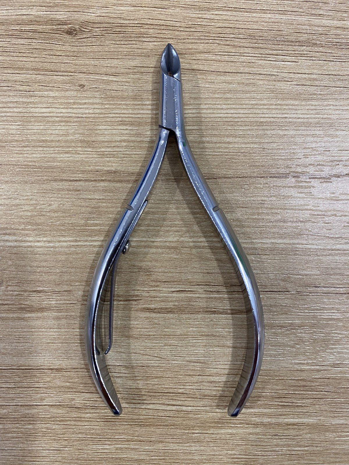 ElisNail semi-round lap joint cuticle nipper on a wooden bench